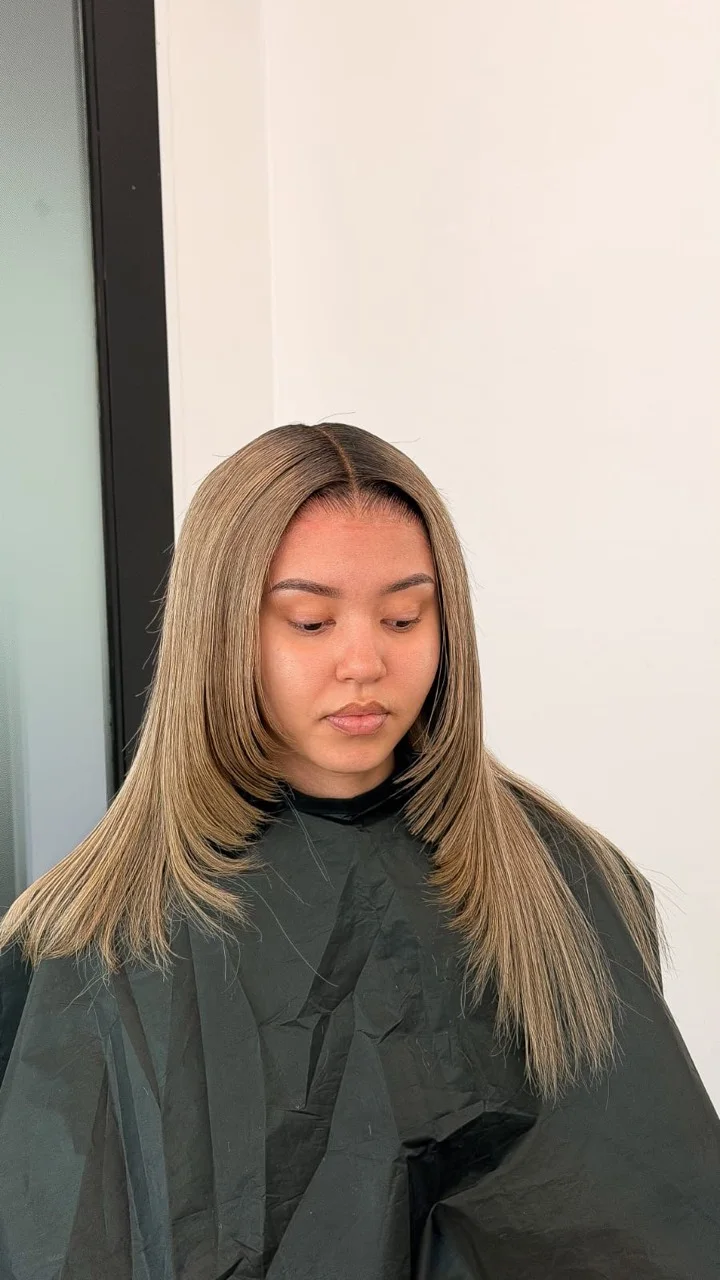 Honey-blonde centre-part hair with smooth face-framing layers by BY LIS